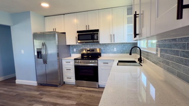 kitchen featuring a sink, light stone countertops, stainless steel appliances, white cabinetry, and backsplash