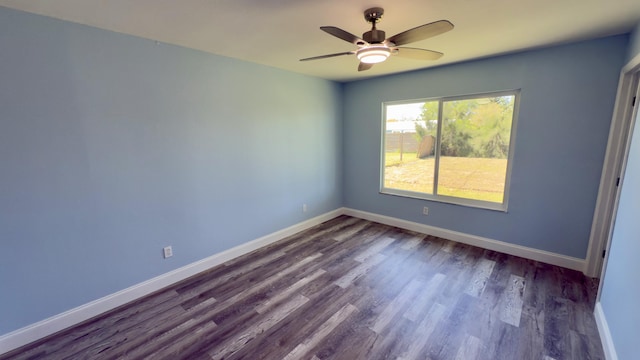 spare room featuring baseboards, dark wood finished floors, and a ceiling fan