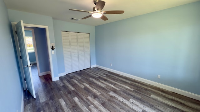 unfurnished bedroom featuring baseboards, visible vents, a ceiling fan, dark wood finished floors, and a closet