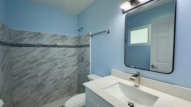 full bathroom featuring tiled shower, vanity, and toilet