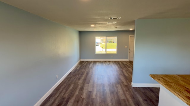 unfurnished room featuring dark wood-style floors, visible vents, baseboards, and recessed lighting