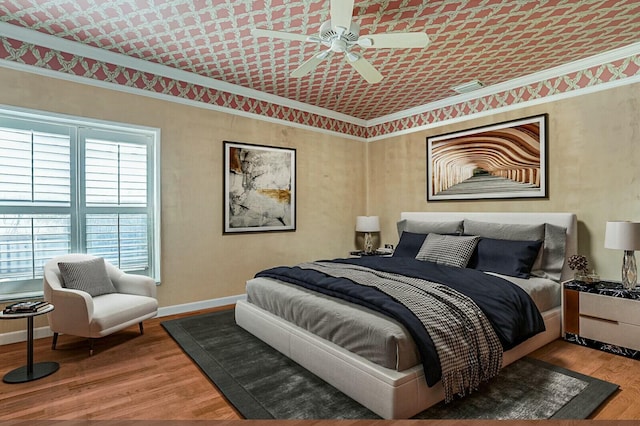 bedroom with ceiling fan, baseboards, wood finished floors, and ornamental molding