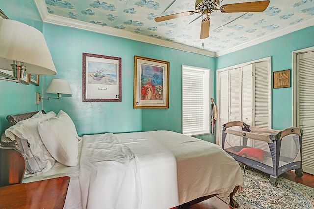 bedroom featuring two closets, crown molding, a ceiling fan, and wood finished floors