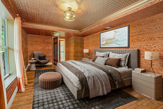 bedroom featuring crown molding, wood finished floors, and a chandelier