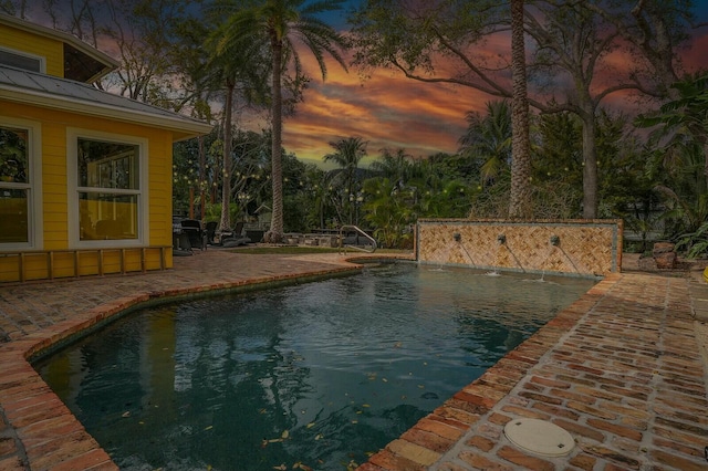 pool at dusk featuring a patio area and an outdoor pool