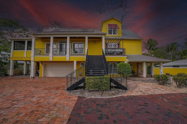 view of front of house featuring stairs, a porch, decorative driveway, and an attached garage