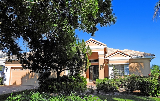 view of front of property featuring stucco siding, a garage, driveway, and a tiled roof