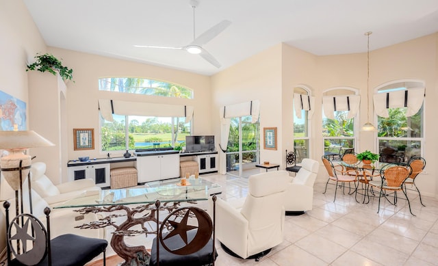 living area featuring light tile patterned floors, a ceiling fan, and a towering ceiling