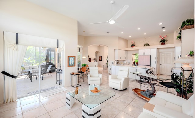 living room with ceiling fan, recessed lighting, arched walkways, light tile patterned floors, and a towering ceiling