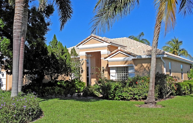 view of front of property with stucco siding, a tile roof, and a front lawn