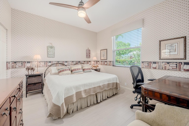 bedroom featuring baseboards, wallpapered walls, ceiling fan, and wood finished floors