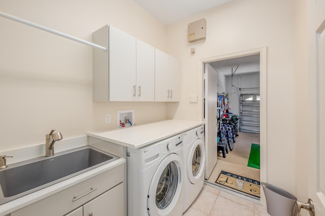 washroom featuring a sink, cabinet space, separate washer and dryer, and light tile patterned floors