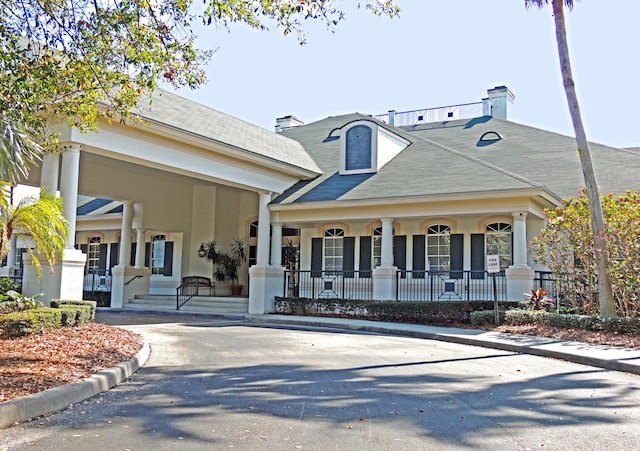 exterior space featuring stucco siding, a porch, and a chimney