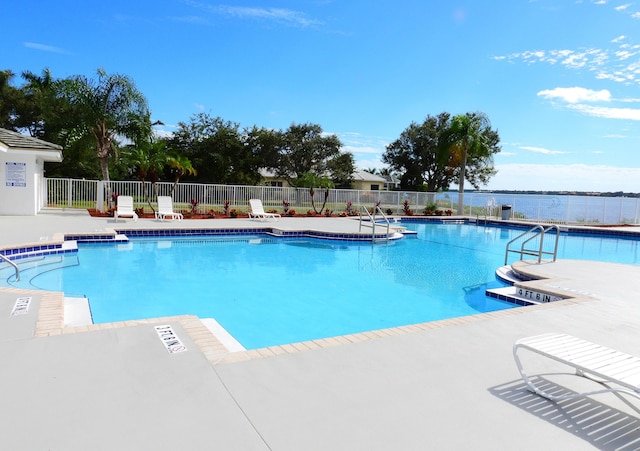 community pool featuring a patio area, fence, and a water view