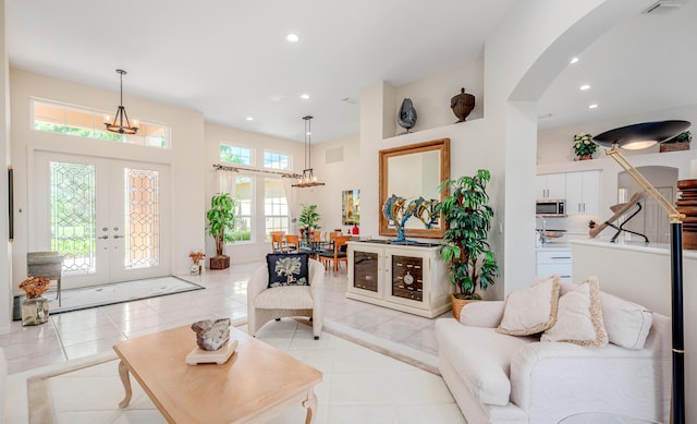 living room with visible vents, light tile patterned flooring, recessed lighting, arched walkways, and french doors