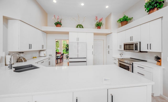 kitchen featuring a sink, appliances with stainless steel finishes, a peninsula, and light countertops