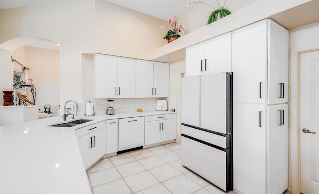 kitchen featuring a sink, white appliances, arched walkways, light countertops, and light tile patterned floors