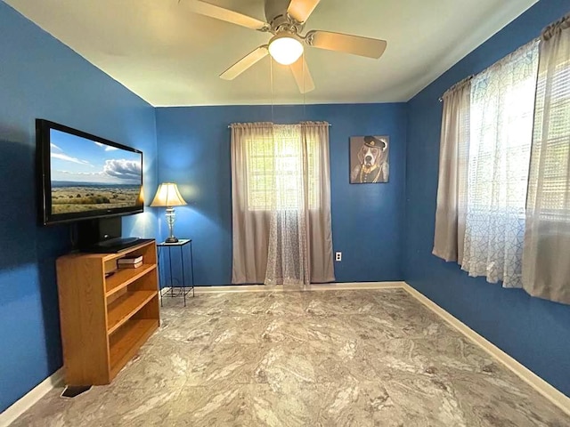 interior space featuring ceiling fan, marble finish floor, multiple windows, and baseboards