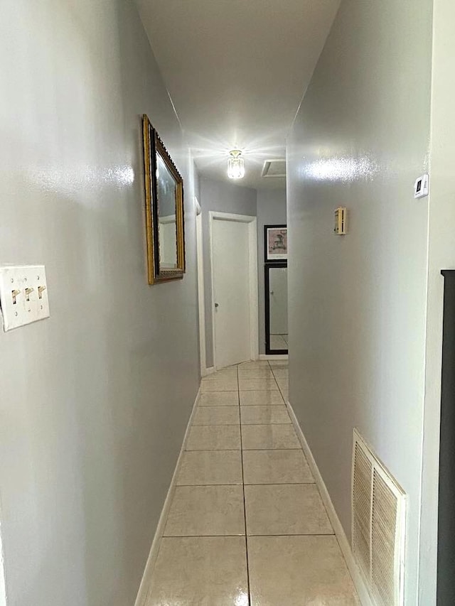 hallway with light tile patterned floors, baseboards, and visible vents