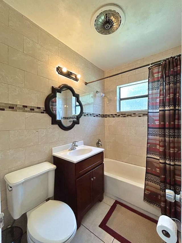 full bathroom with toilet, shower / tub combo with curtain, tile patterned floors, vanity, and tile walls