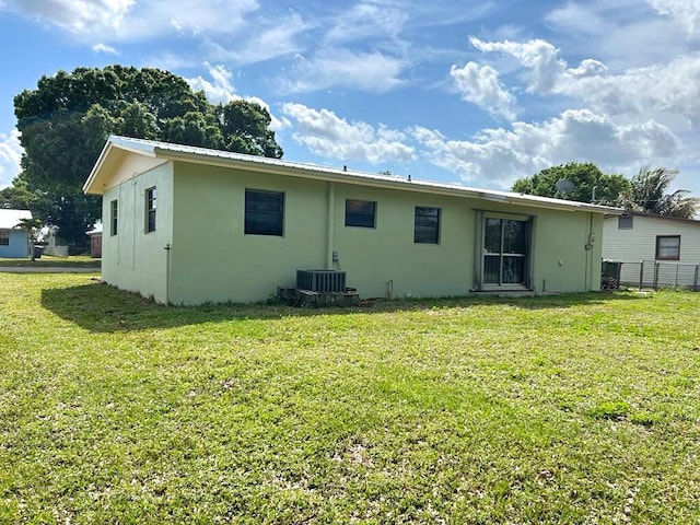 back of house with metal roof, central AC, a yard, and stucco siding