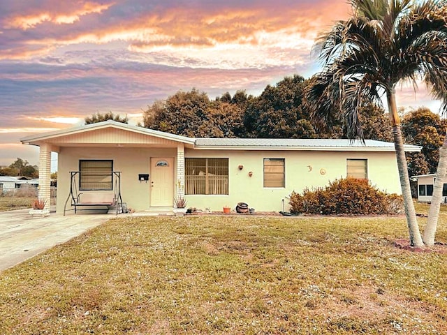 ranch-style house featuring metal roof, a front lawn, and stucco siding