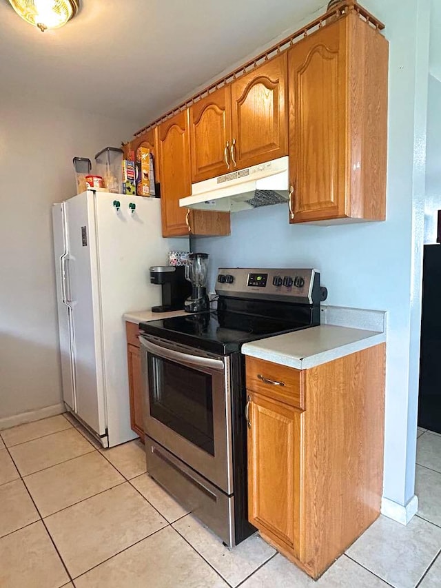 kitchen featuring brown cabinets, freestanding refrigerator, stainless steel electric stove, light countertops, and under cabinet range hood