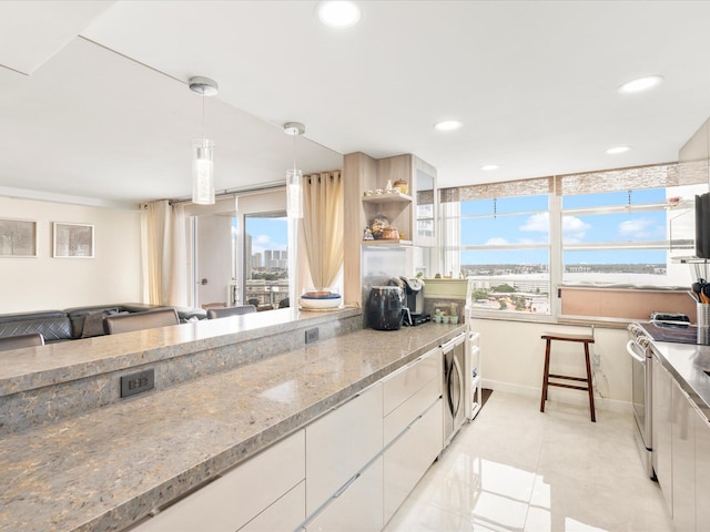 kitchen with hanging light fixtures, washer / clothes dryer, a healthy amount of sunlight, and stainless steel electric stove