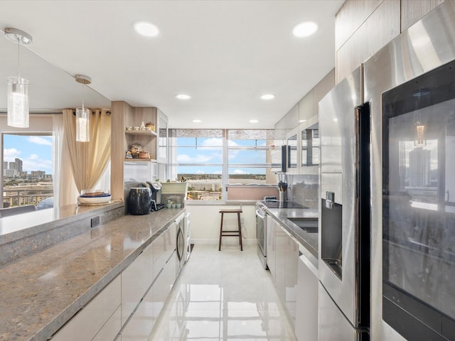 kitchen featuring stainless steel appliances, modern cabinets, light stone countertops, and a healthy amount of sunlight