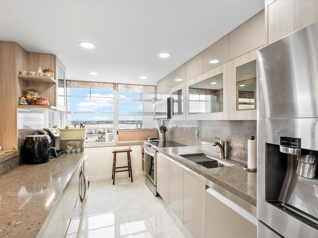 kitchen with a sink, stainless steel refrigerator with ice dispenser, decorative backsplash, light stone countertops, and electric range oven