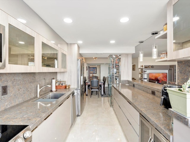 kitchen with appliances with stainless steel finishes, decorative backsplash, a sink, and light stone countertops