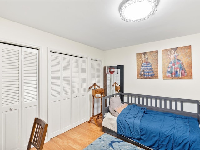 bedroom with light wood-style flooring and two closets