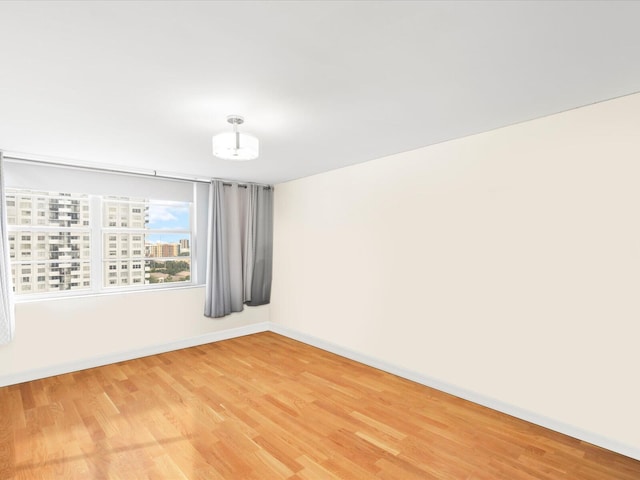 empty room featuring light wood-type flooring and baseboards