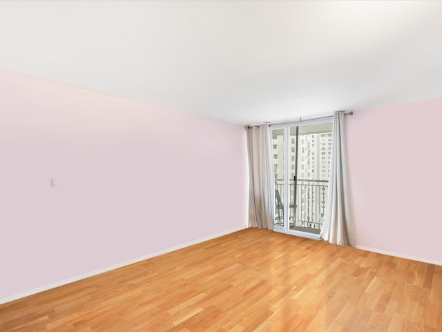 spare room with baseboards, floor to ceiling windows, and light wood-style floors