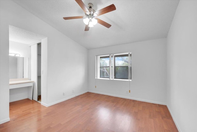 unfurnished bedroom featuring vaulted ceiling, wood finished floors, baseboards, and a textured ceiling