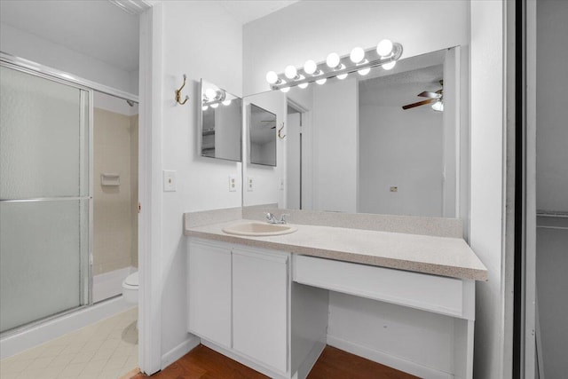 full bathroom featuring ceiling fan, toilet, a stall shower, and vanity