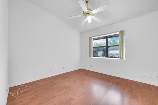 spare room with a ceiling fan, lofted ceiling, baseboards, and wood finished floors