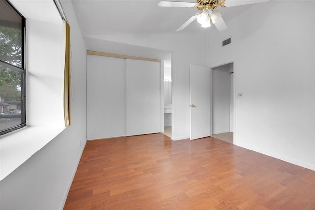 unfurnished bedroom featuring visible vents, wood finished floors, a closet, ceiling fan, and vaulted ceiling