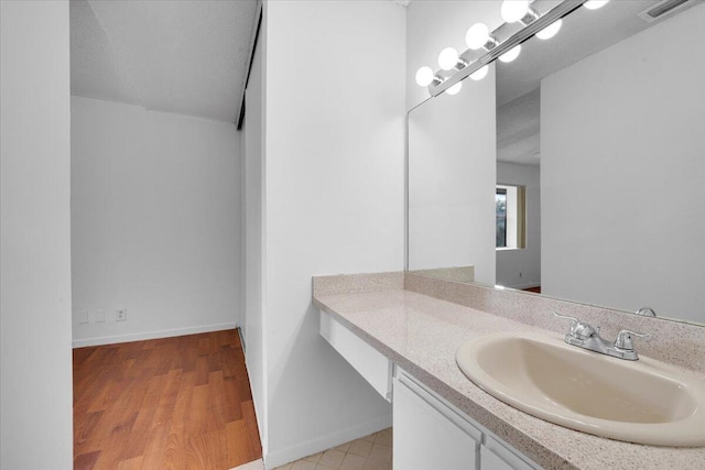 bathroom with visible vents, vanity, baseboards, and wood finished floors