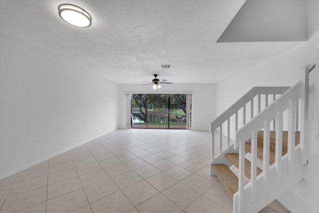 interior space with visible vents, ceiling fan, stairs, light tile patterned floors, and a textured ceiling