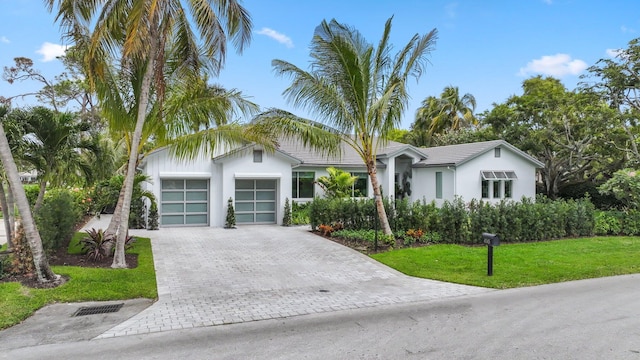 view of front of home featuring a garage, decorative driveway, a front yard, and stucco siding