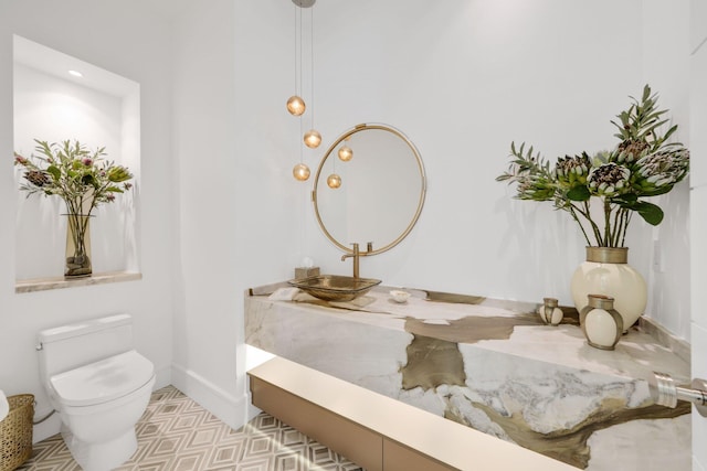 half bathroom featuring baseboards, a sink, and toilet