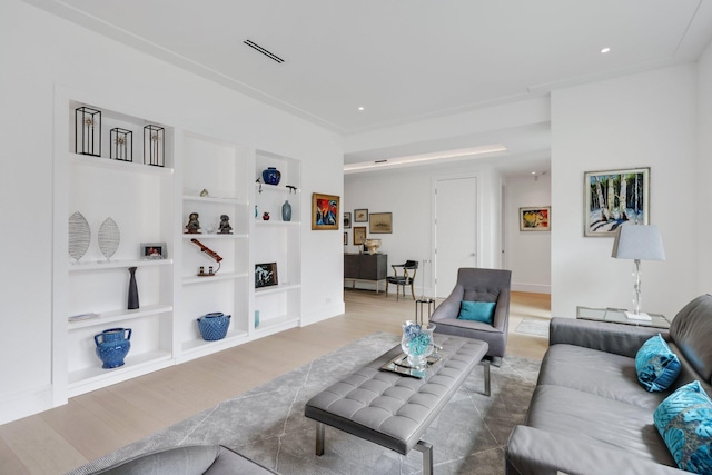 living area with built in shelves, recessed lighting, and wood finished floors