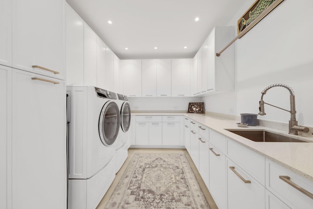 clothes washing area featuring washing machine and dryer, light wood-style flooring, recessed lighting, a sink, and cabinet space