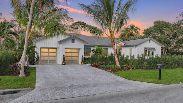 view of front of property featuring a yard, decorative driveway, an attached garage, and stucco siding