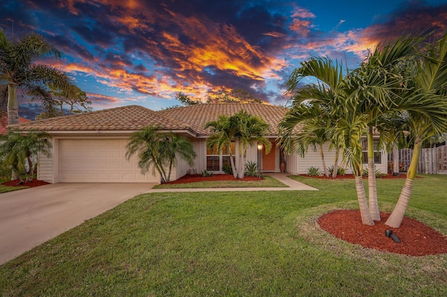 mediterranean / spanish home with a garage, concrete driveway, a yard, and a tile roof