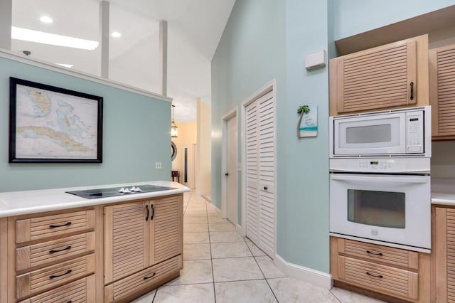 kitchen with light tile patterned floors, light countertops, high vaulted ceiling, white appliances, and baseboards