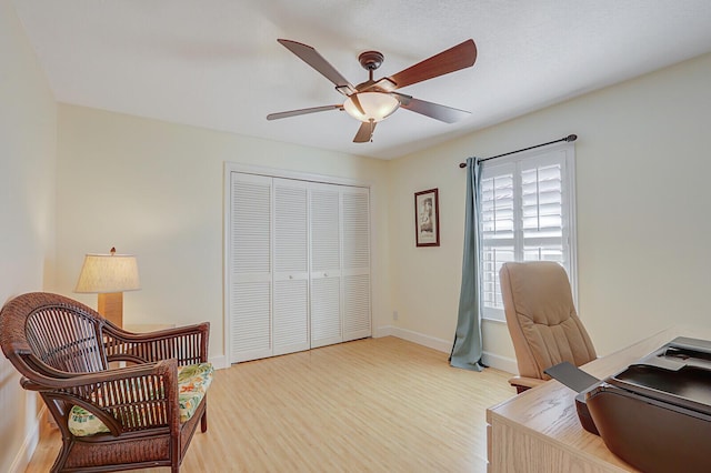 office area featuring light wood finished floors, baseboards, and a ceiling fan