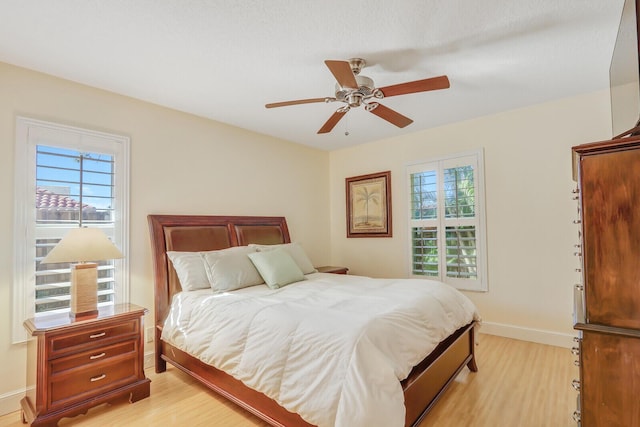 bedroom featuring light wood-type flooring, baseboards, and a ceiling fan