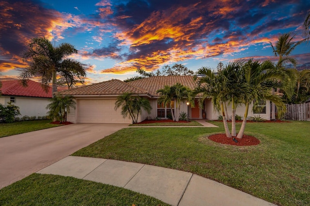 view of front of home featuring driveway, a tile roof, an attached garage, a yard, and stucco siding